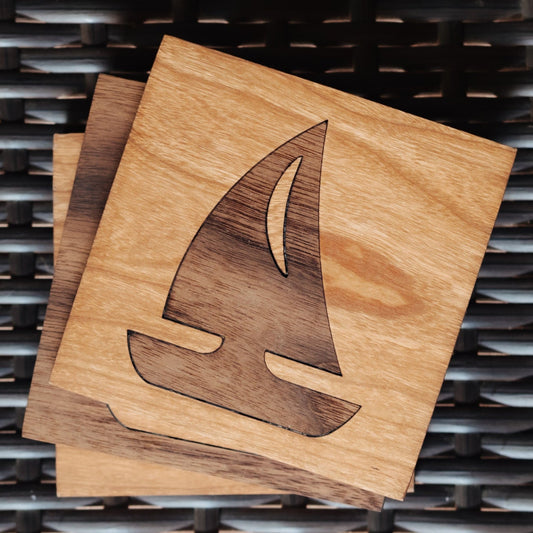 Two square wooden coasters stacked on top of each other, featuring a laser-engraved sailboat design