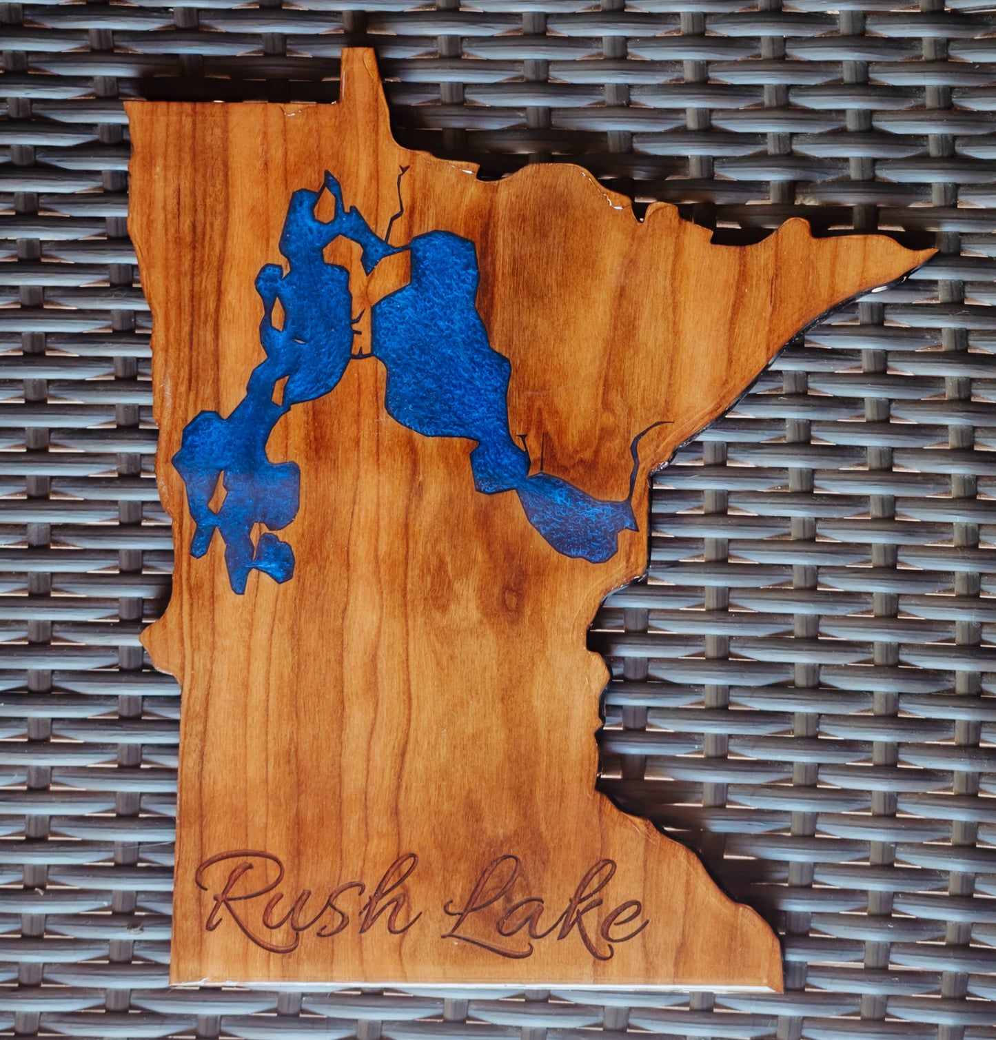 A wooden plaque shaped like the state of Minnesota, featuring a blue resin map of Rush Lake and the words 'Rush Lake' engraved at the bottom,