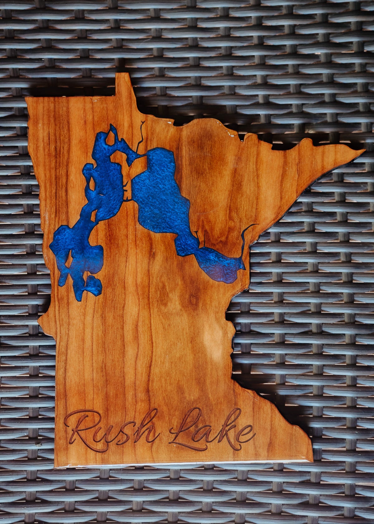 A wooden wall art plaque shaped like the state of Minnesota, featuring a blue inlay of Rush Lake and the words 'Rush Lake' engraved at the bottom