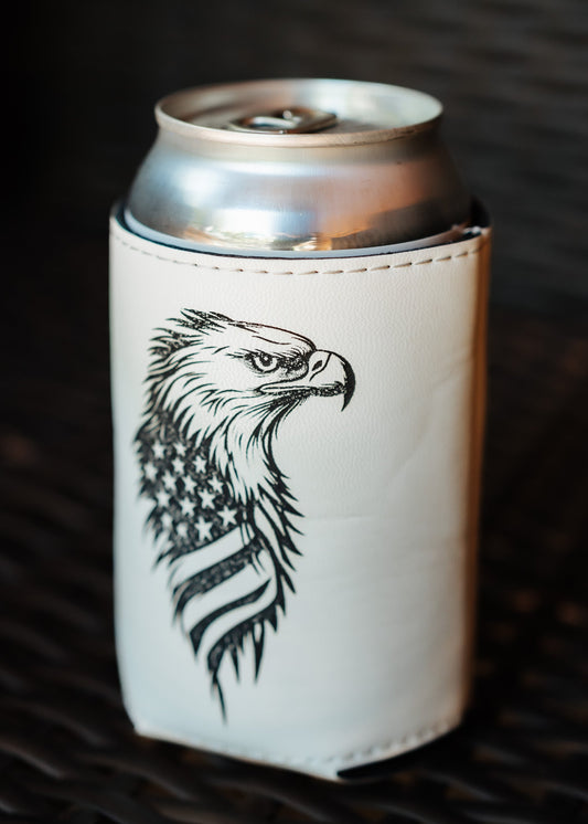 A white insulated can cooler sleeve with a black graphic of an eagle head and stars-and-stripes pattern