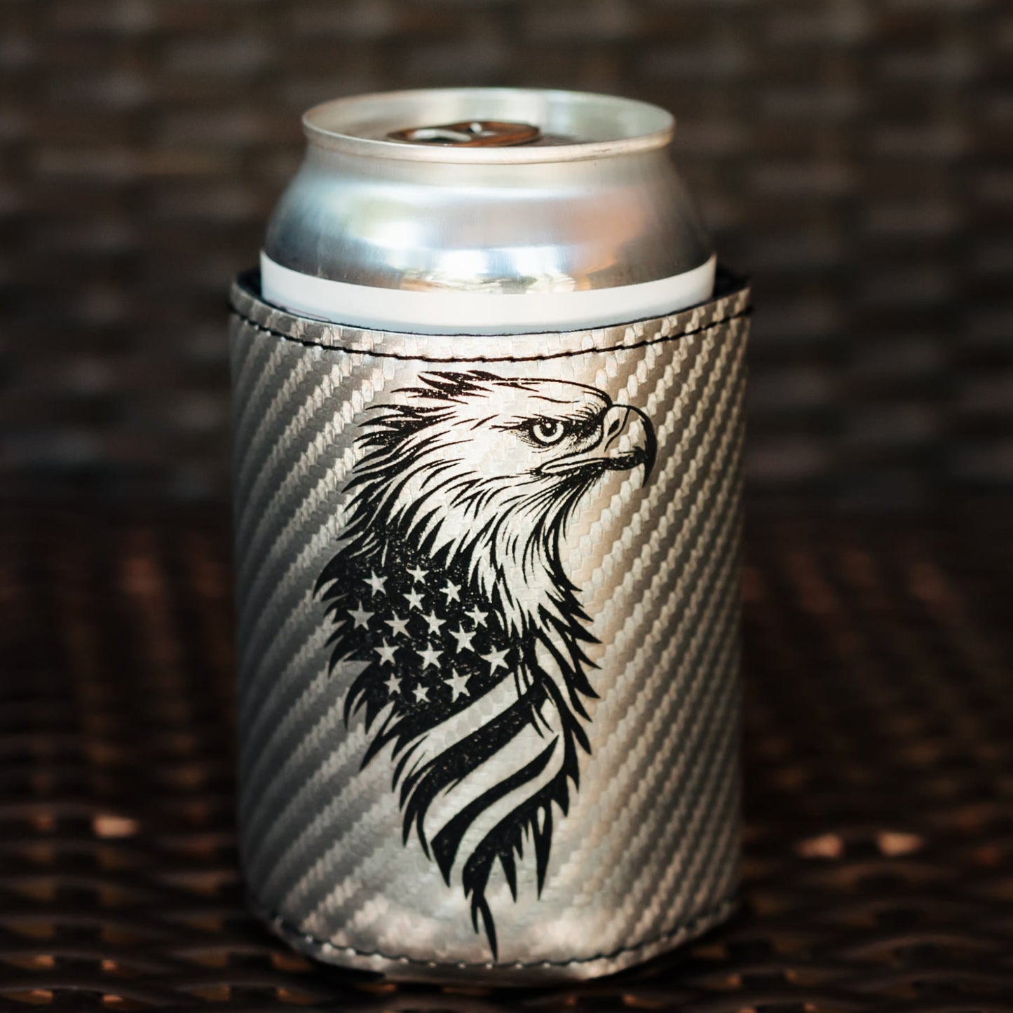 A silver can cooler sleeve with a black eagle and American flag design