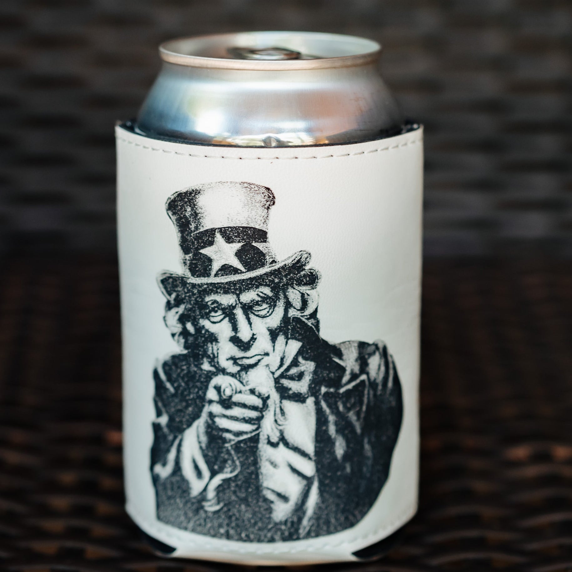A white insulated can cooler sleeve with a black-and-white illustration of Uncle Sam on the fron