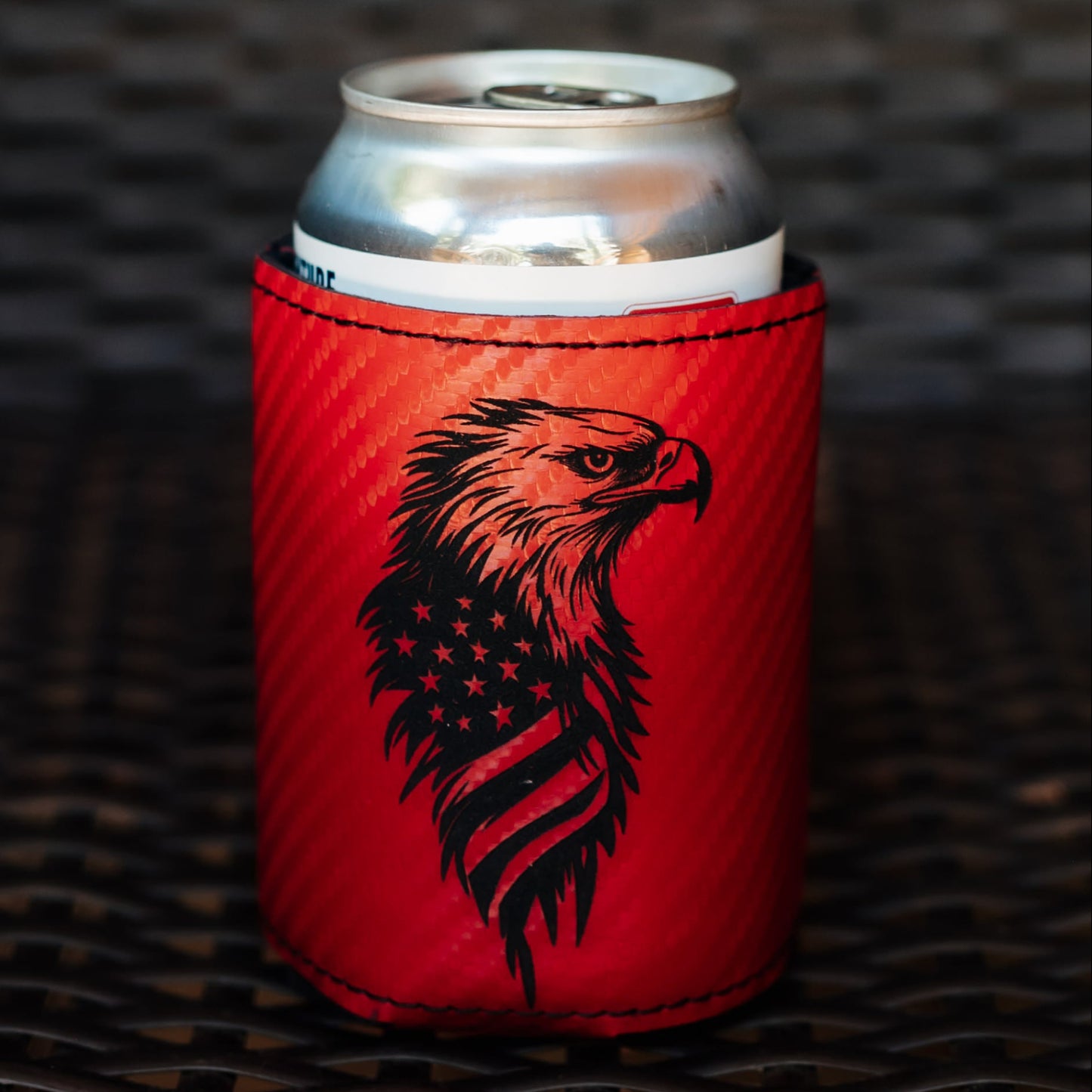 A red can cooler sleeve with a black eagle graphic 