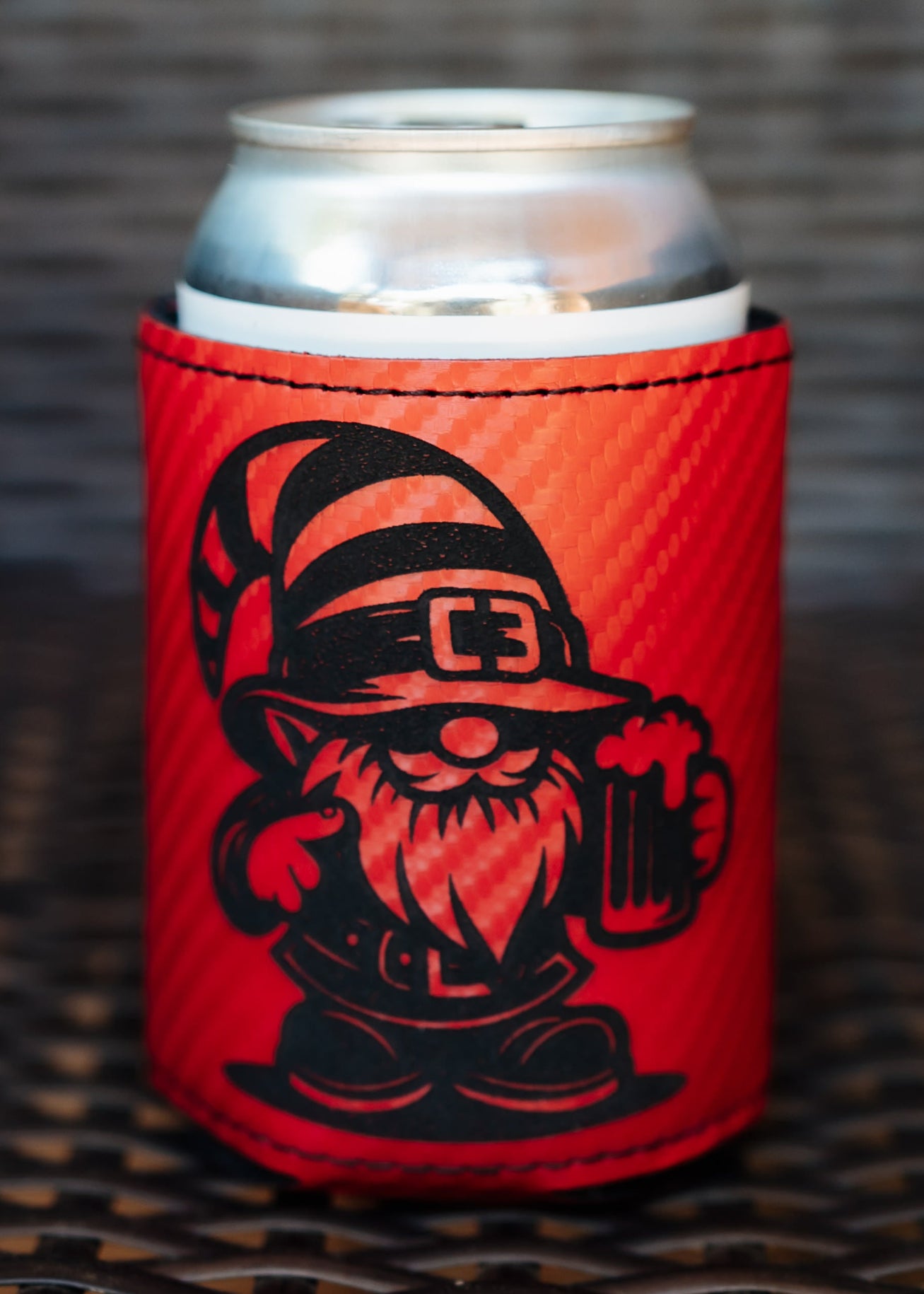A red can cooler sleeve with a black gnome graphic holding a mug